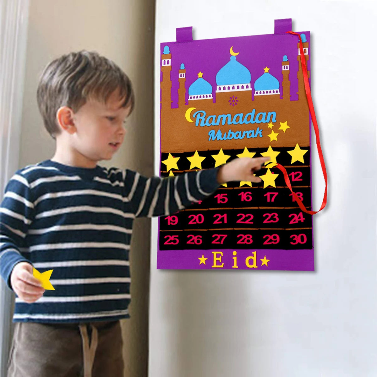 Child interacting with a Ramadan countdown calendar on a wall.