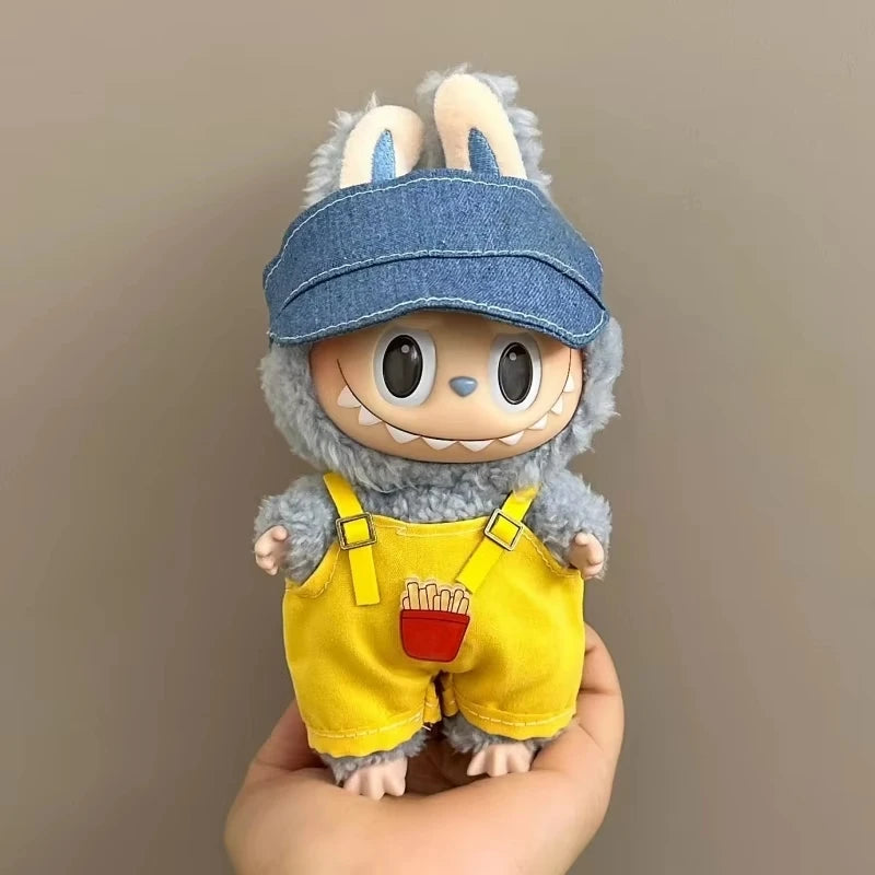 Toy figure with a denim cap and yellow overalls held against a plain background