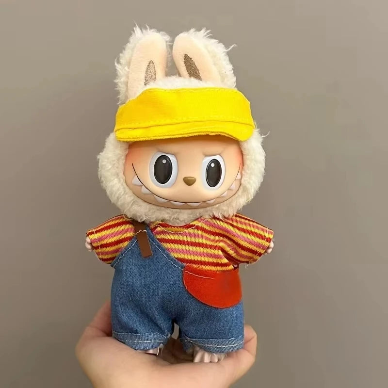 Toy figure with bunny ears, yellow cap, striped shirt, and denim overalls held against a plain background.
