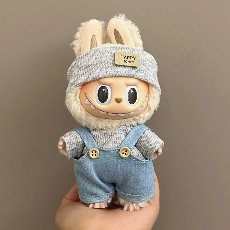 Toy figure with bunny ears and denim overalls held against a plain background